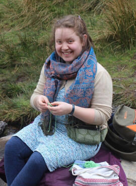 image of Frances crocheting near a stream